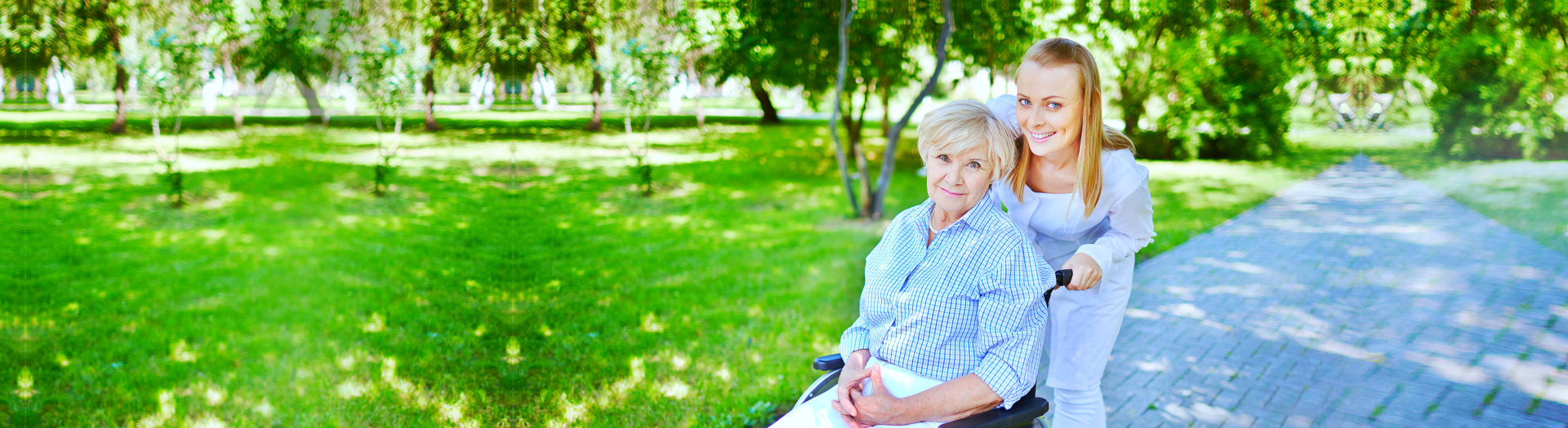 Female caregiver walking with senior patient in park